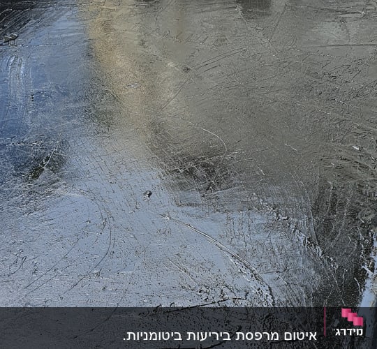 משטח אטום בזפת שחורה עם קיר מתקלף ברקע